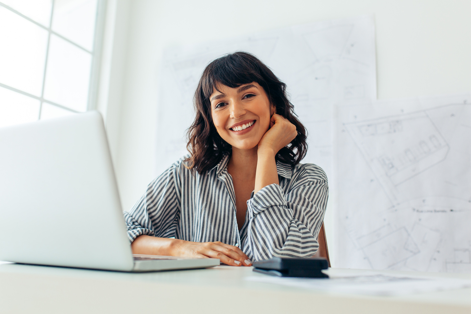 Smiling female architect sitting at her office desk