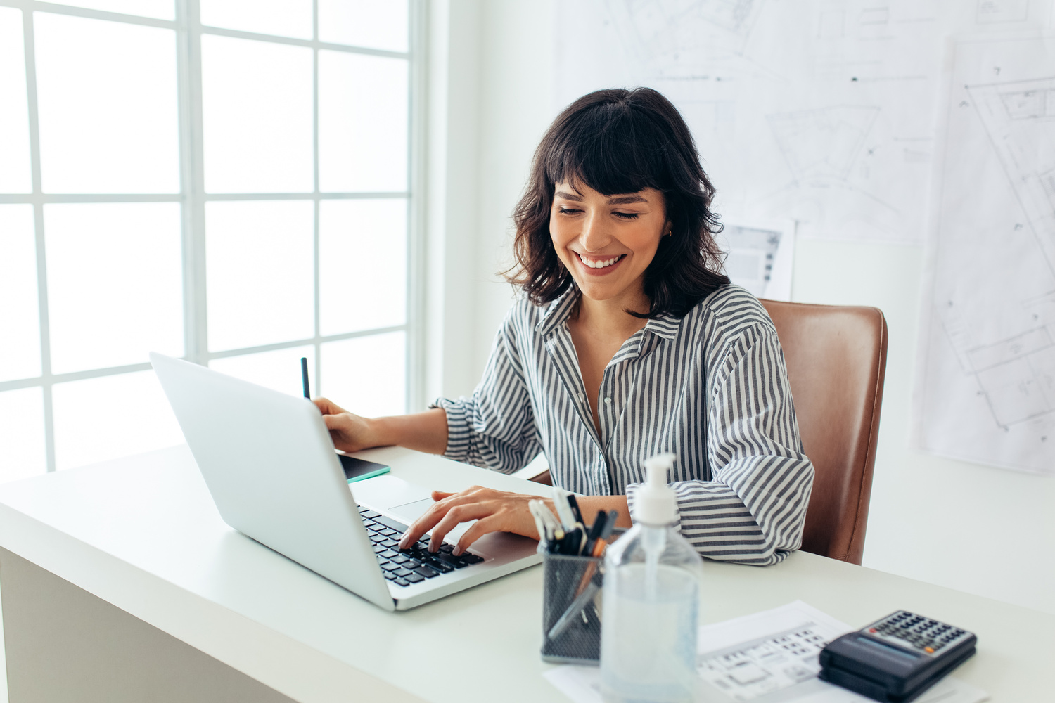 Cheerful woman sitting at her office desk and working