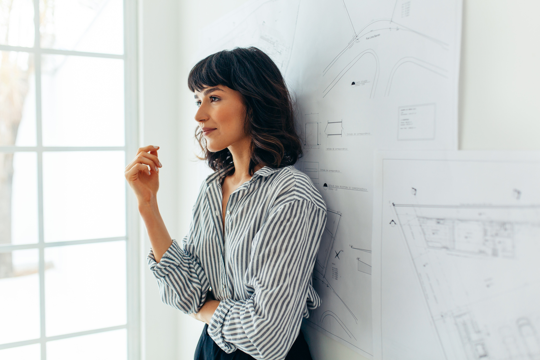 Confident female architect standing near drawings